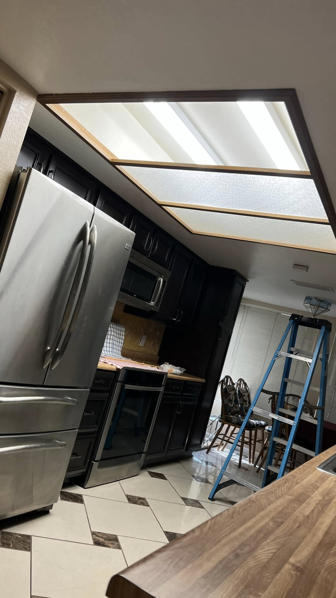Kitchen mid-job — fluorescent panels pulled, prepping for can lights